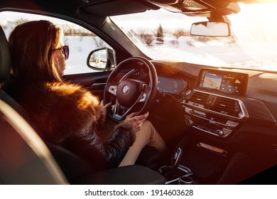 Riga, Latvia 10 February 2021 BMW X4 G02 driving in snowy countryside road. 
Woman is driving the car in winter city with Sun lense flare. 