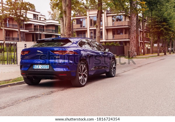 Riga Latvia\
17 September 2020 Jaguar I-Pace Compact luxury battery-electric\
crossover SUV standing at parking slot on street. Led lights on.\
Private village with\
houses.