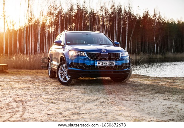 Riga, Latvia 19 February 2020 The Škoda Karoq\
is a subcompact crossover manufactured by the Czech automaker Škoda\
Auto. Stands in forest road in Sunset mood. Blue Škoda on Green\
forest background.
