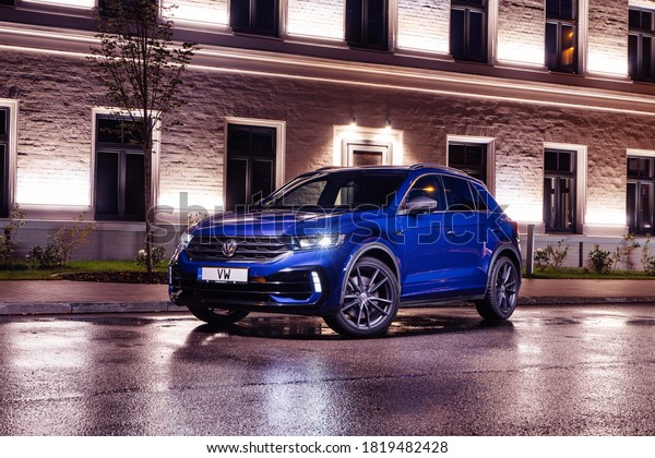 Riga,\
Latvia 19 September 2020 Volkswagen T-Roc R stands on parking lot\
by house at night time after rain. Led lights on.\

