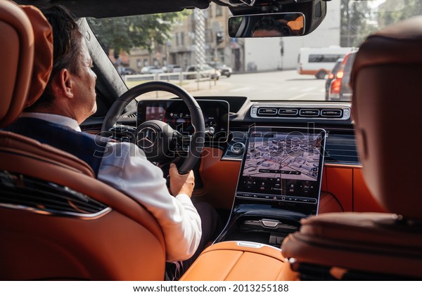 Riga, Latvia 21 July 2021\
Limousine transfer chauffeur driving luxury car in cityscape.\
Private driver of Mercedes Benz S500 S class w223, view from rear\
seats.\
