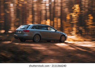 Riga, Latvia 21 October 2021: Audi A6 3.0 TDI Quattro driving through the autumn forest on a sunny day, blurred auto in fast motion with a blurred autumn background.