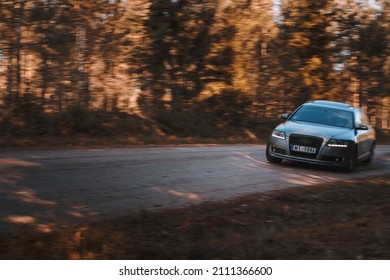 Riga, Latvia 21 October 2021: Front view of Audi A6 3.0 TDI Quattro drifting in the sunny autumn forest, auto in fast motion with a blurred background.