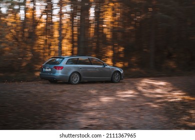 Riga, Latvia 21 October 2021: Fast driving Audi A6 3.0 TDI Quattro on a forest road during a sunny autumn day, blurred forest background