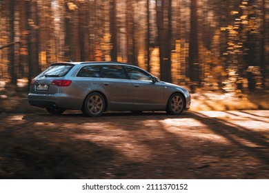 Riga, Latvia 21 October 2021: Rear view of Audi A6 3.0 TDI Quattro driving through the autumn forest on a sunny day, auto in fast motion with blurred autumn background, focus on the back of the car
