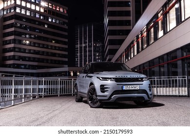 Riga Latvia 27 April 2022, Range Rover Evoque Plug-in Hybrid Brand New Model. Stand On Parking Lot In Modern Office Buildings At Night Time, Led Light On. Front Side View.