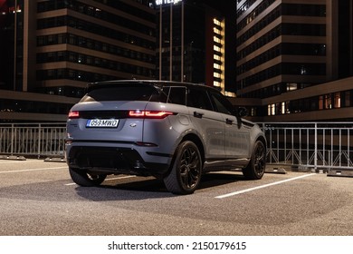 Riga Latvia 27 April 2022, Range Rover Evoque Plug-in Hybrid Brand New Model. Stand On Parking Lot In Modern Office Buildings At Night Time, Led Light On. Rear Side View.