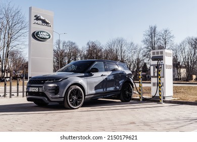 Riga Latvia 27 April 2022, Range Rover Evoque Plug-in Hybrid Brand New Model. Stand On Parking Lot In Modern Office Buildings At Night Time, Led Light On. Stands On Parking Lot By Charging Station