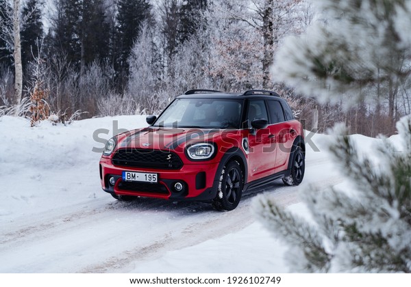Riga, Latvia 28 February\
2021 Mini Cooper S Countryman Plug in Hybrid Facelift model driving\
in country side snowy road, Led lights on. MINI John Cooper Works\
package.