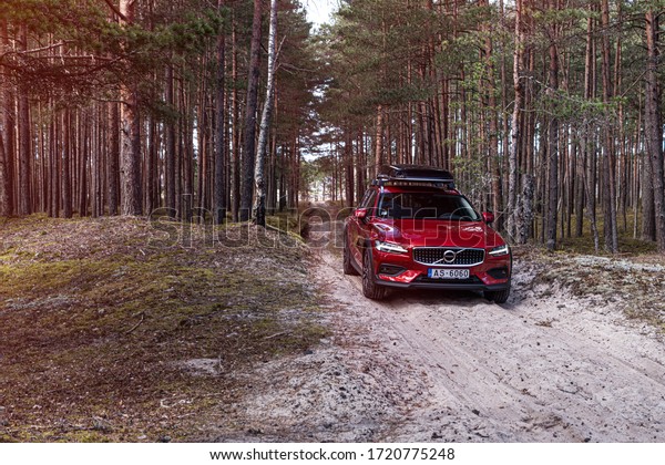 Riga, Latvia 3 May 2020,\
Volvo V60 Cross Country with roof box, Stands on sand mug forest\
road. Green forest landscape sunset background. Countryside mood\
adventure. 