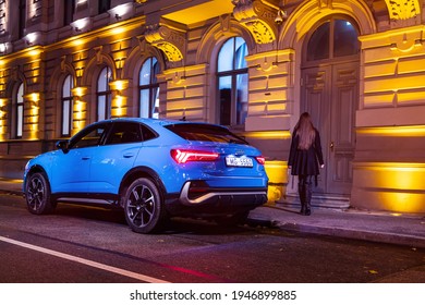 Riga, Latvia 31 March 2021 Audi Q3 Sportback  Blue Colour. Stands On Street At Night Time, Background Woman Is Walking Home. Small City SUV.