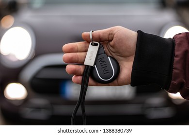 Riga, Latvia 4 May 2019 Mini Keyring In Hand. Man Holding Mini Cooper Keys With Key Chain Front Of Mini Car.