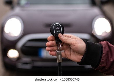 Riga, Latvia 4 May 2019 Mini Keyring In Hand. Man Holding Mini Cooper Keys With Key Chain Front Of Mini Car.