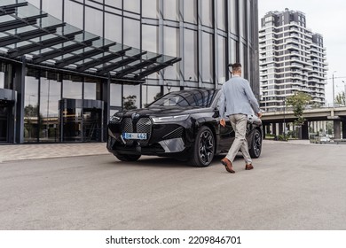 Riga Latvia, 4 October 2022, BMW IX I20 M Sport Mid-size Luxury Crossover SUV, Black Color Car Stand By Entrance To Office House. Sport SUV Electric Vehicle By BMW. Man Walking To BMW. Business Man.