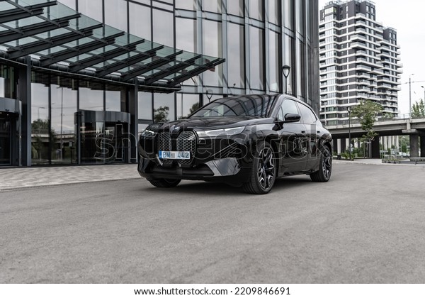 Riga Latvia, 4 October 2022, BMW iX i20 M Sport\
mid-size luxury crossover SUV, Black color car stand by Entrance to\
Office House. Sport SUV electric vehicle by BMW stands on parking\
lot by office.