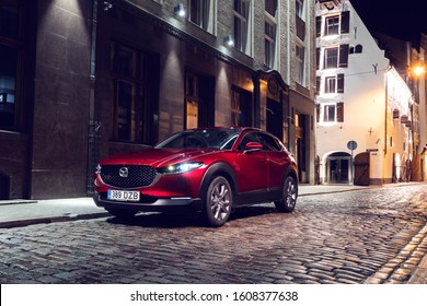 Riga, Latvia 7 January 2020 The Mazda CX-30 is a compact crossover SUV produced by Mazda. Stands on parking slot classic house, side view, background old city. Red Mazda with light on. 