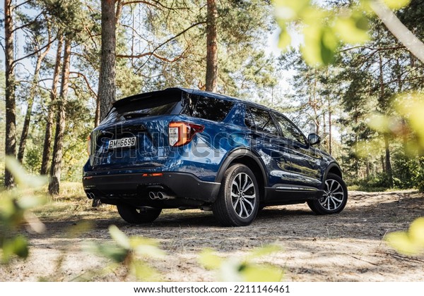 Riga, Latvia 7 October\
2022 The sixth-generation Ford Explorer Plug-in Hybrid An optional\
twin-turbocharged 3.0 L EcoBoost V6 stand in pine forest at sunny\
day mood.