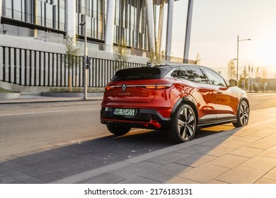 Riga, Latvia 8 July 2022, Renault Megane E-Tech Electric Is A Battery Electric-powered Small Family Car. Business Centre Modern Buildings. Stands On Parking Lot At Sunset Light Mood.