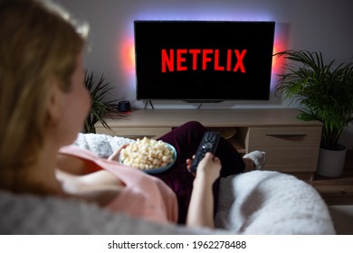 Riga, Latvia - April 14, 2021: Woman watching TV at home with Netflix logo on the screen.
