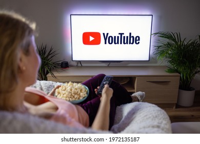 Riga, Latvia - April 14, 2021: Woman Holding Popcorn And Watching TV At Home With YouTube Logo On The Screen.