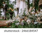 Riga, Latvia, - August 26, 2023 - Close-up of a wedding bouquet on the ground with the blurred bride and groom in the background during their outdoor ceremony.