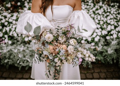 Riga, Latvia, - August 26, 2024 - Close-up of a bride holding a colorful bouquet, with a white floral background. - Powered by Shutterstock