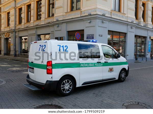 Riga, Latvia - July\
7, 2020: A Citroen brand police car drives down a street with blue\
flashing lights on