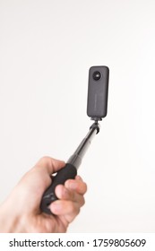 Riga, Latvia - June 19, 2020: Hand Holding Selfie Stick With Insta360 One X 360 Camera Isolated On White Background