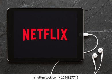 Riga, Latvia - March 25, 2018: Earphones connected to iPad showing Netflix logo on the screen.