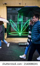 Riga, Latvia, May 21, 2022 A Large Neon Marijuana Leaf Adorns A Window Of A Coffee Shop.