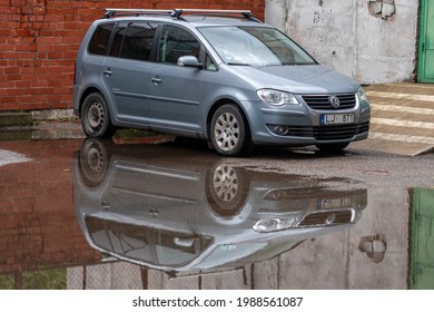 Riga, Latvia, May 26, 2021:  Family Minivan VW Touran Full Reflection In The Yard Puddle After The Rain, Close-up