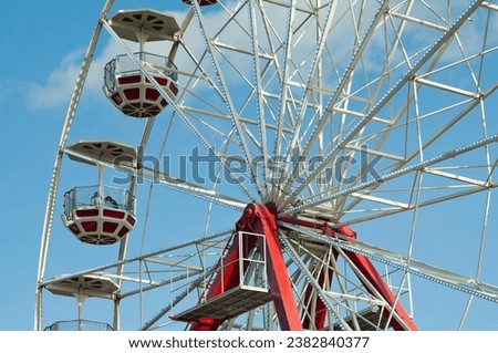 Riga, Latvia – September 24, 2023: 
 Ferris wheel in an amusement park against a blue sky.