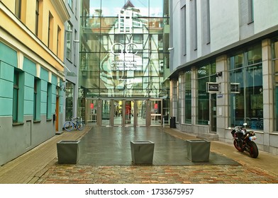 Riga, Latvia-16.05.2020:the Entrance To The Shopping Centre GALERIJA CENTRS. The Photo Shows The Mirror Wall Of The Center And The Reflection Of The Old City Building In It, As Well As A Parked Motorc