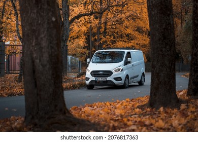 Riga, Latvia-October 6, 2021: White Ford Transit Custom commercial vehicle driving on the city street during the beautiful autumn leaf fall