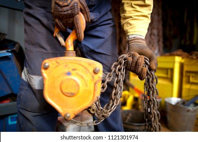 Rigger high risk worker wearing heavy duty CS5 hand protection glove, doing checking inspection a heavy duty 3 tones yellow lifting chains block prior used on construction site Perth city, Australia  - Powered by Shutterstock