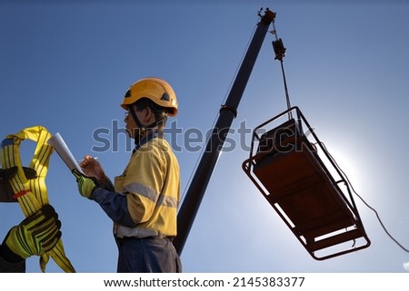 Rigger inspector high risk worker   inspecting checking yellow three lifting sling with red danger tag safety glove personal lock tags helmet prior used construction building site, Australia 
