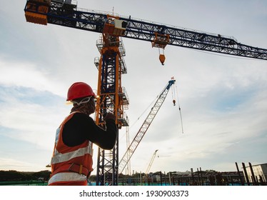  Rigger signal crane at construction site with walkie;talkie 