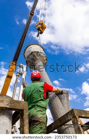 Rigger, worker with safety helmet disassembles pump canal for vertical charging, pouring fresh concrete into bridge foundation on river coast.