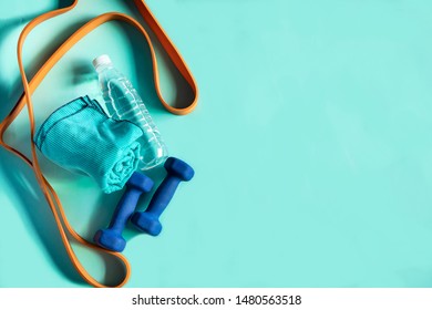 Right Above View Blue Background Close Up Dumbbells Mineral Water Towel And Elastic Band And Other Fitness Products