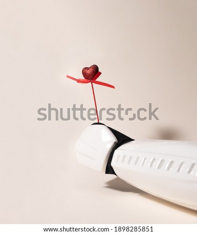 From right bottom side Storm trooper hand is offering red glittery heart on pink wood stick on a beige background with a shadow. Shoot taken from eye level. Give a present concept.