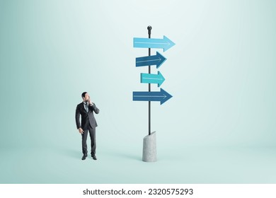 Right choice, dilemma and business strategy direction concept with pensive man in black suit looking at signpost with blue arrows in different direction on abstract light background