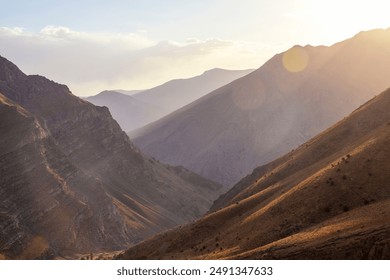 In the right corner is the sun and the fall of light from the sun on the layered perfect mountains. Wonderful sequential mountains, a light fog, the silhouette of the mountains and the valley. Travel.