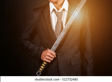 The right hand of a businessman holding a sword on a dark background. vintage effect.
