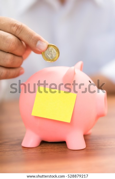 Right hand fill coin piggy saving bank,\
empty note on piggy bank, saving money\
concept.