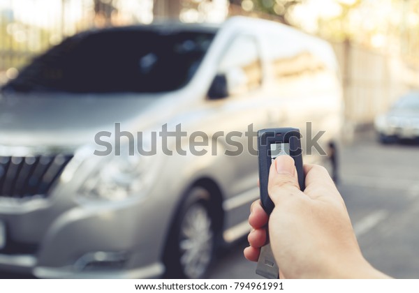 right hand\
hole remote car and press buttom to unlock door car with blur car\
park on background, vintage tone\
effect