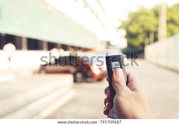 right hand
hole remote car and press buttom to unlock door car with blur car
park on background, vintage tone
effect