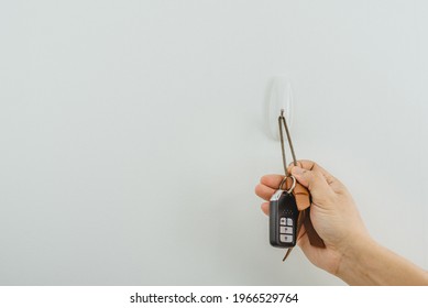 The Right Hand Is Picking Up Or Taking The Keychain, Car Key From Hanger At The Wall. 