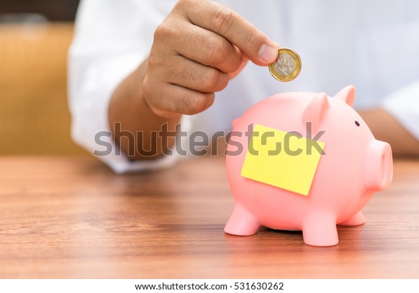 Right hand putting add coin\
to picky pig banking, empty note on piggy bank, saving money\
concept.