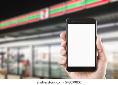 Right Hand Using Smartphone With Blank Screen On Abstract Blur Background Of Front Of Convenience Store At Night View