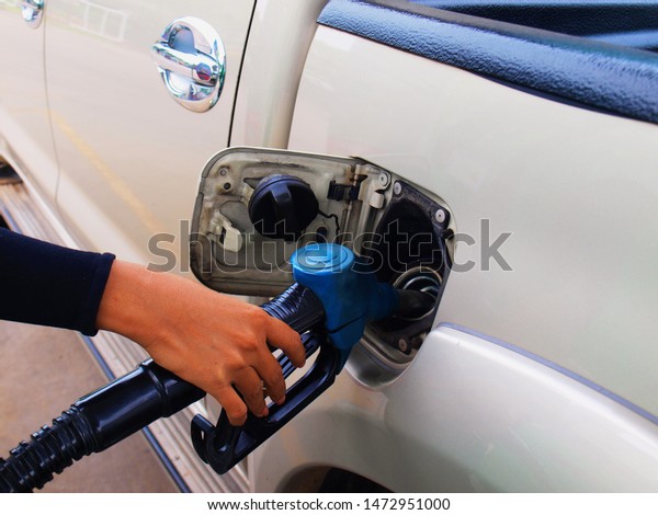 The right\
hand woman is holding the fuel pump nozzle and is filling the fuel\
in the pickup truck at the gas\
station.